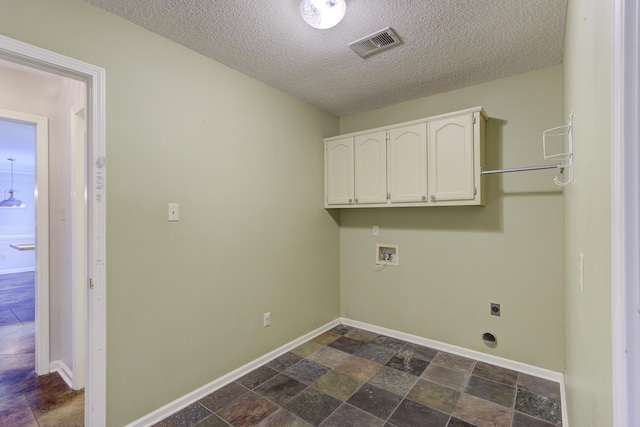 clothes washing area with hookup for a washing machine, cabinets, a textured ceiling, and hookup for an electric dryer