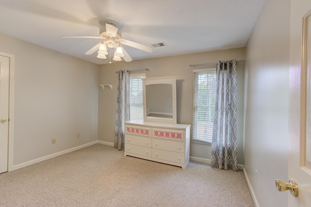 unfurnished bedroom with ceiling fan, a textured ceiling, and light carpet