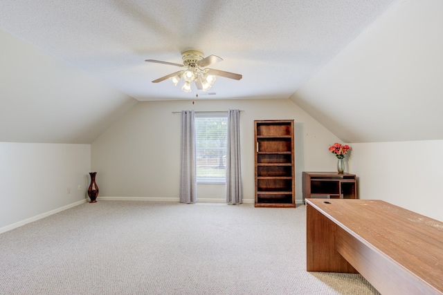 unfurnished office featuring carpet flooring, a textured ceiling, lofted ceiling, and ceiling fan