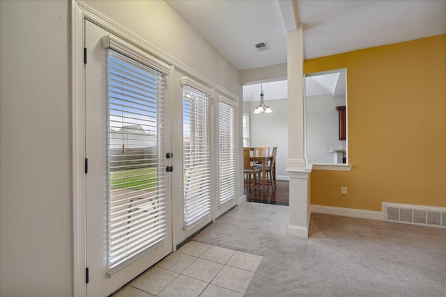 entryway featuring a wealth of natural light, light colored carpet, and an inviting chandelier