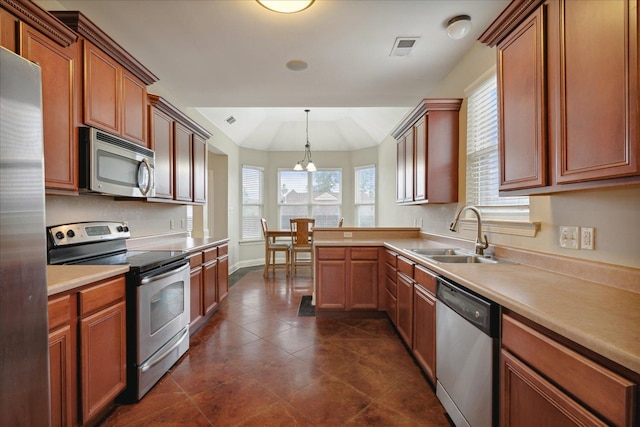 kitchen with appliances with stainless steel finishes, lofted ceiling, sink, and decorative light fixtures