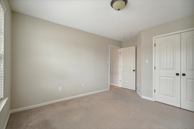 unfurnished bedroom featuring light colored carpet and a closet