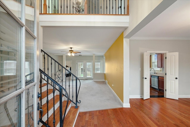 foyer with sink, ceiling fan with notable chandelier, hardwood / wood-style floors, crown molding, and french doors