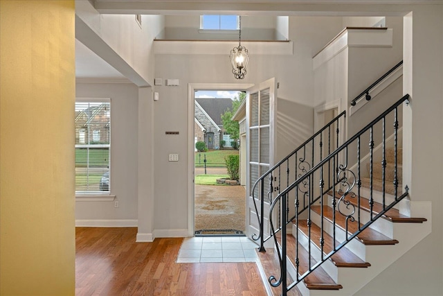 foyer entrance featuring wood-type flooring, a notable chandelier, and ornamental molding