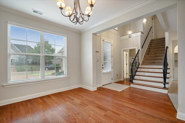 foyer with hardwood / wood-style flooring, crown molding, and a notable chandelier