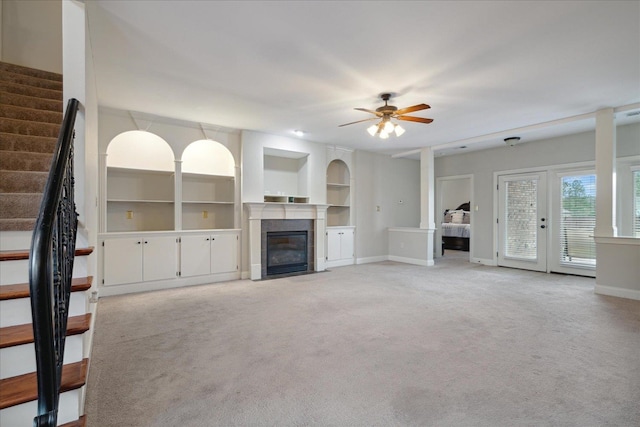 unfurnished living room featuring built in shelves, light carpet, and ceiling fan