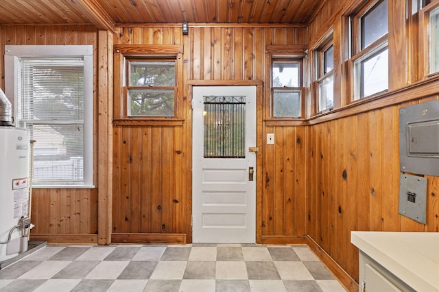 entryway featuring a healthy amount of sunlight, wooden walls, gas water heater, and wooden ceiling