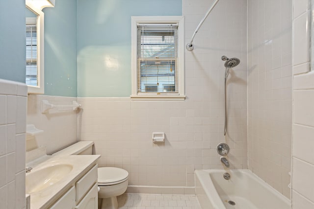 full bathroom featuring toilet, tile patterned floors, tile walls, tiled shower / bath, and vanity