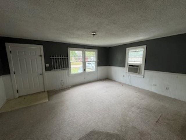 carpeted empty room with a wealth of natural light, cooling unit, and a textured ceiling