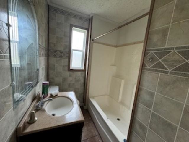 bathroom with vanity, a textured ceiling, a shower, and tile walls