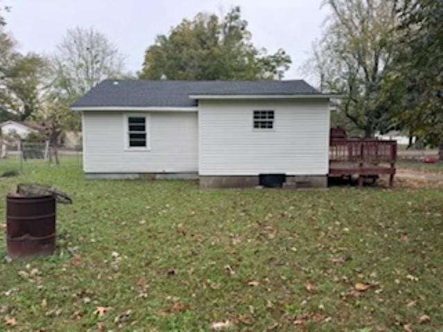 view of property exterior featuring a deck, a lawn, and an outdoor structure