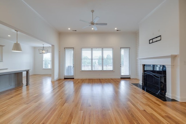 unfurnished living room featuring a tiled fireplace, ceiling fan, plenty of natural light, and light hardwood / wood-style flooring