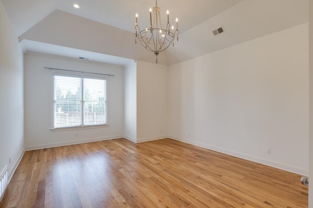 empty room featuring lofted ceiling, light wood-type flooring, and a notable chandelier