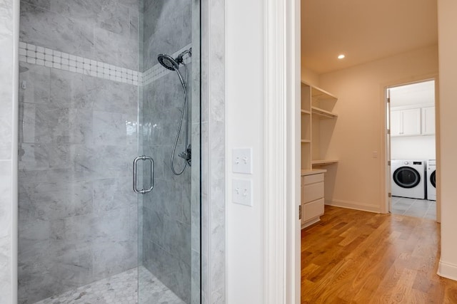 bathroom featuring a shower with door, washer and clothes dryer, and wood-type flooring