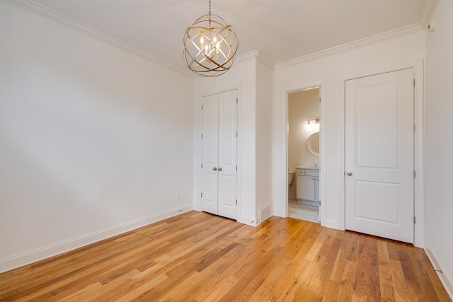 unfurnished bedroom with light hardwood / wood-style floors, ornamental molding, connected bathroom, and a chandelier