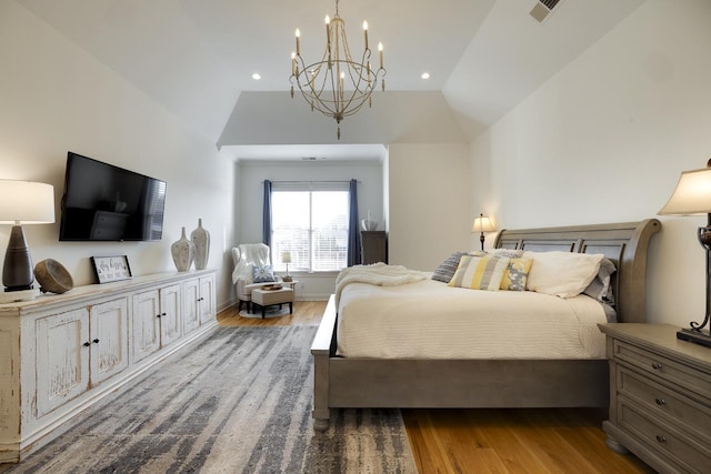 bedroom with hardwood / wood-style floors, vaulted ceiling, and a notable chandelier