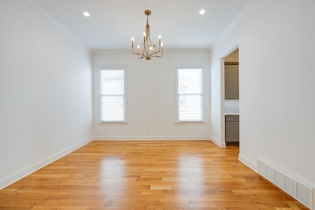 spare room featuring light wood-type flooring, an inviting chandelier, plenty of natural light, and crown molding