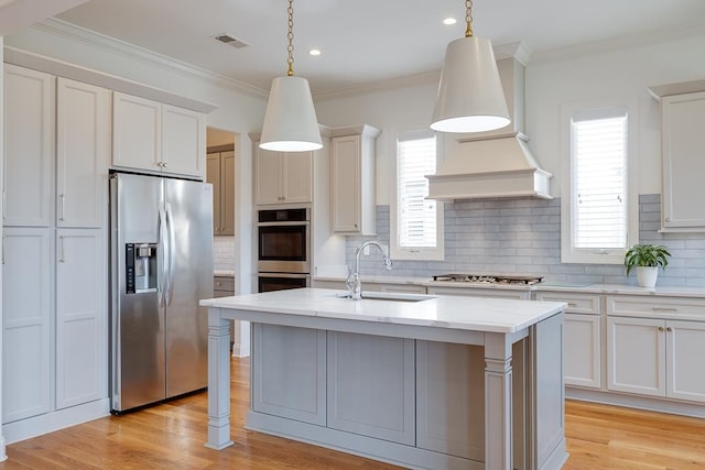 kitchen featuring pendant lighting, stainless steel appliances, a center island with sink, and sink