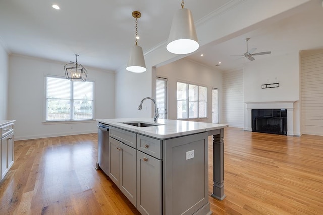 kitchen with a tile fireplace, sink, an island with sink, pendant lighting, and gray cabinets