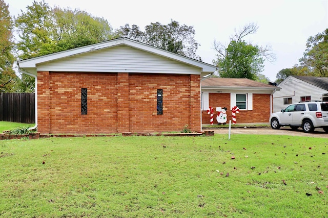 view of front facade featuring a front yard, fence, and brick siding