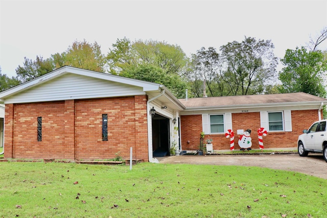 ranch-style house featuring a garage, brick siding, driveway, and a front lawn