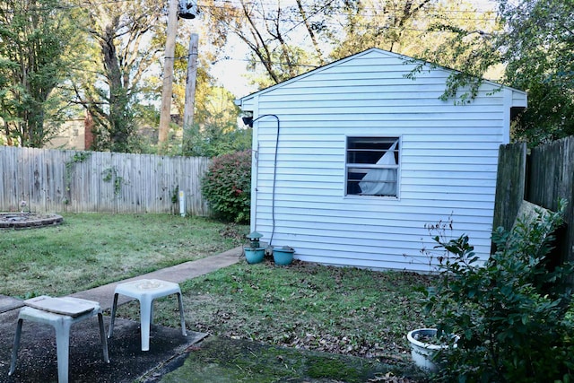 view of side of home with a fenced backyard, an outbuilding, and a yard