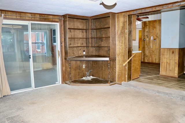 carpeted empty room with wooden walls and a ceiling fan