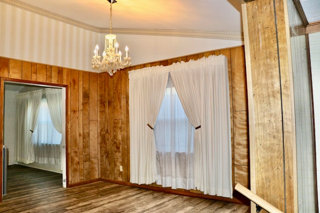 unfurnished room featuring wood walls, wood finished floors, and an inviting chandelier