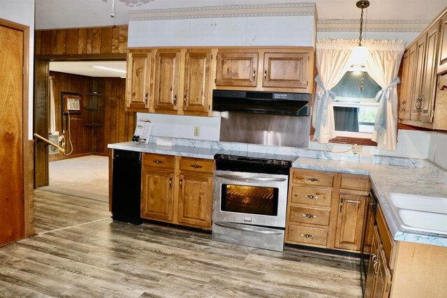 kitchen with light wood-style flooring, wooden walls, under cabinet range hood, electric stove, and light countertops