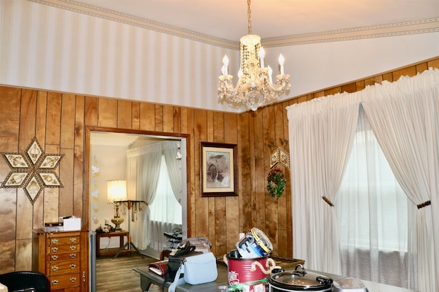 dining area with wood walls, wood finished floors, and a notable chandelier