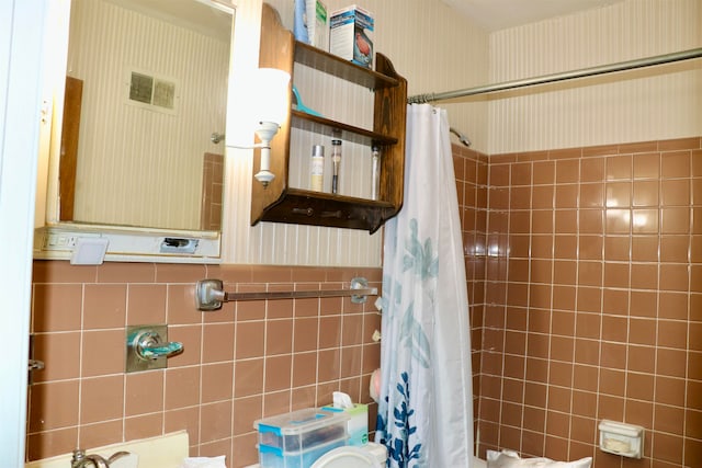 bathroom with wallpapered walls, visible vents, wainscoting, shower / bathtub combination with curtain, and tile walls