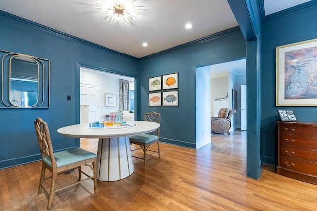 dining room with light wood-type flooring and crown molding