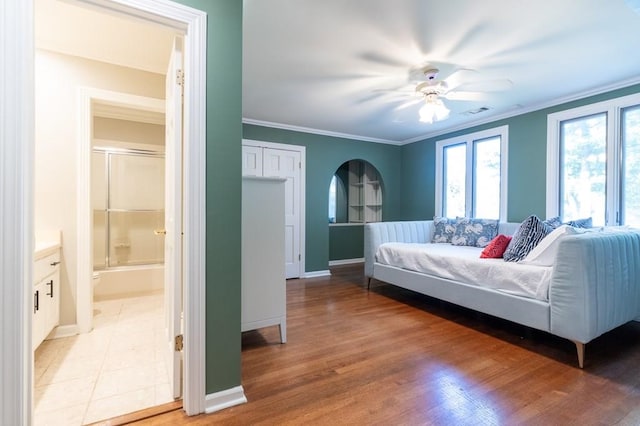 bedroom featuring connected bathroom, ornamental molding, wood-type flooring, and ceiling fan