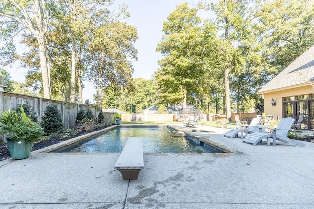 view of pool with a diving board and a patio