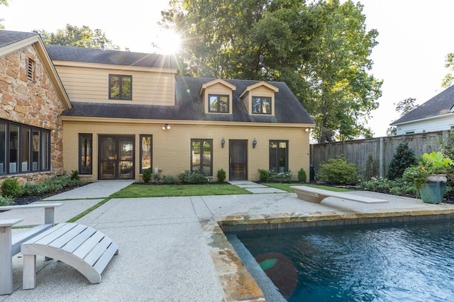 rear view of property with a fenced in pool and a patio area