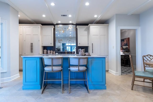 kitchen with a kitchen island, white cabinetry, and a kitchen bar