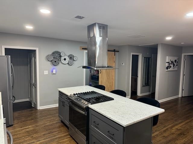 kitchen with island exhaust hood, gray cabinets, dark wood-type flooring, and appliances with stainless steel finishes