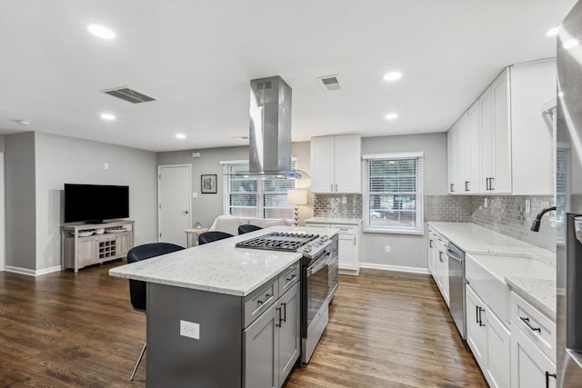 kitchen featuring island exhaust hood, appliances with stainless steel finishes, dark hardwood / wood-style flooring, and white cabinets