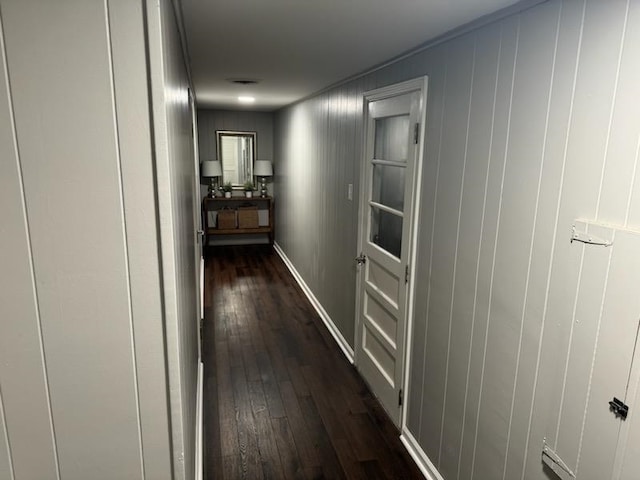 hallway featuring wooden walls and dark wood-type flooring