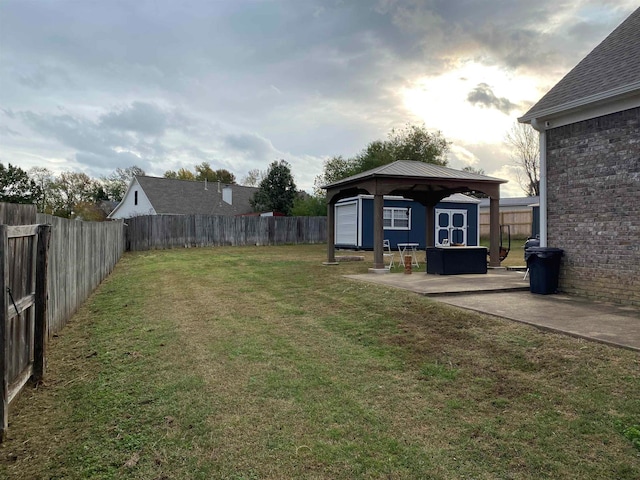 view of yard featuring an outbuilding, a gazebo, a patio area, and a fenced backyard