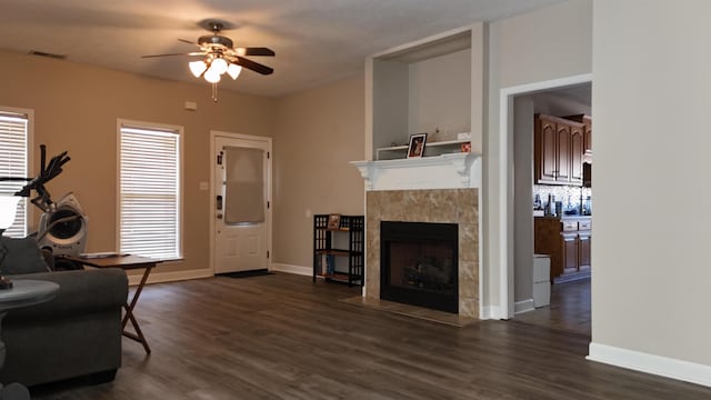 living area featuring dark wood-style floors, ceiling fan, a fireplace, and visible vents