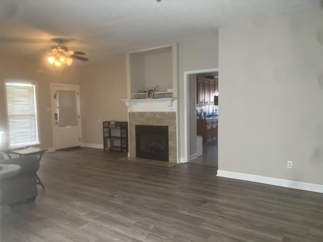 living area with a fireplace, baseboards, dark wood finished floors, and a ceiling fan