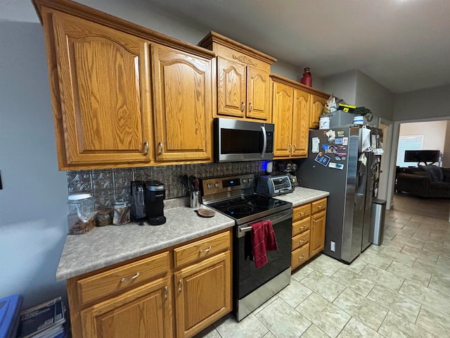 kitchen with appliances with stainless steel finishes, brown cabinetry, backsplash, and a toaster