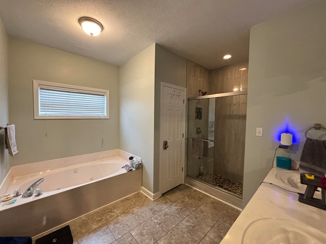 full bath featuring double vanity, baseboards, a tub with jets, a textured ceiling, and a shower stall