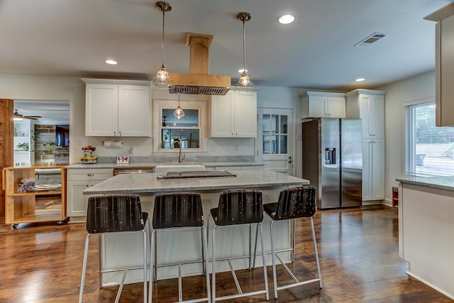 kitchen featuring white cabinets, stainless steel fridge, dark wood-type flooring, and hanging light fixtures