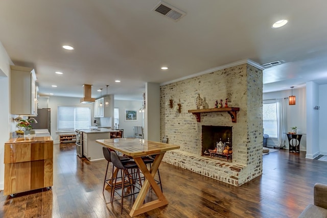 dining area featuring a brick fireplace and dark hardwood / wood-style flooring