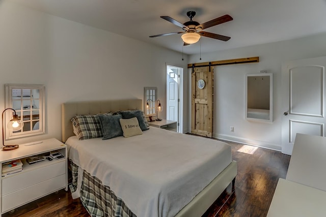 bedroom with ceiling fan, dark hardwood / wood-style floors, and a barn door