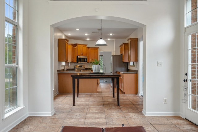 kitchen featuring pendant lighting, stainless steel appliances, a breakfast bar, and plenty of natural light