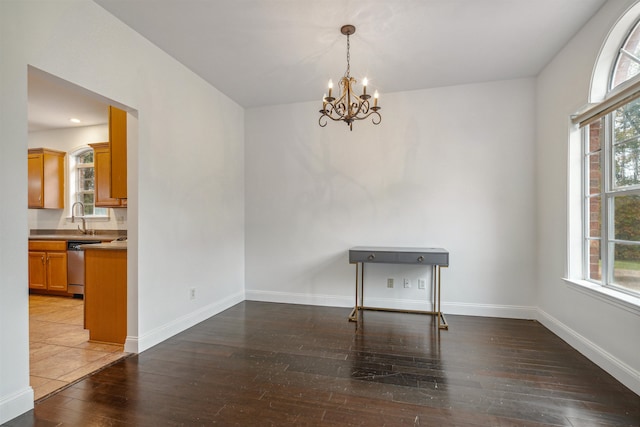 unfurnished dining area with a wealth of natural light, dark wood-type flooring, a chandelier, and sink