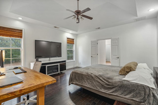 bedroom featuring ceiling fan, dark hardwood / wood-style floors, and a raised ceiling